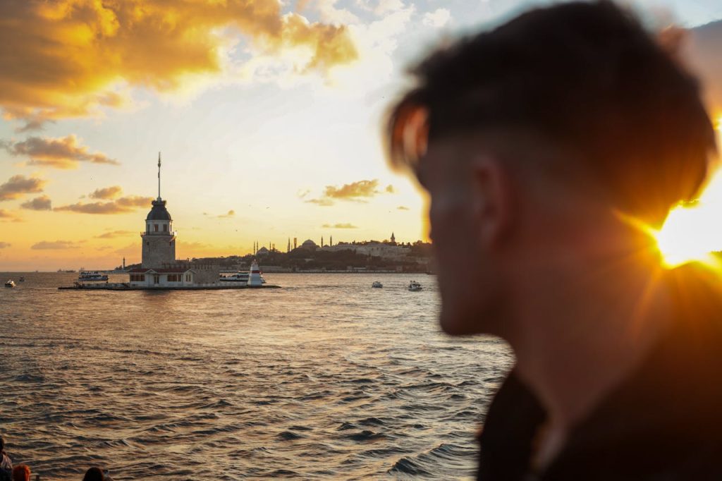 A silhouette in foreground with the historic Maidens Tower against a stunning Istanbul sunset over the sea.